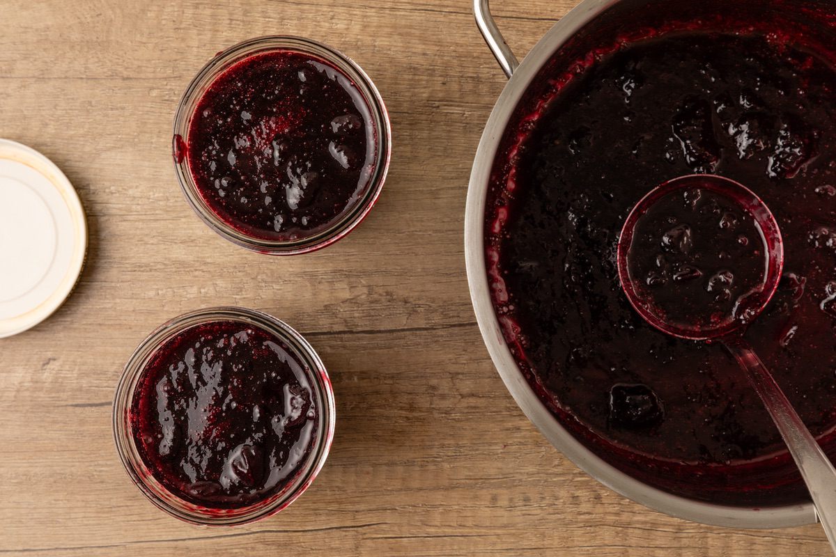 adding cherry jam into jars